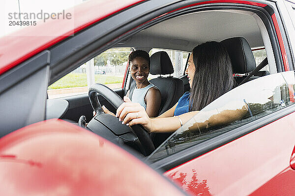 Smiling female friends sitting in red car