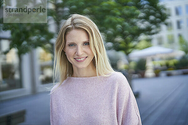 Smiling woman wearing purple sweater at street