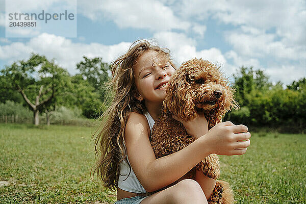 Girl with Maltipoo dog sitting in farm on sunny day