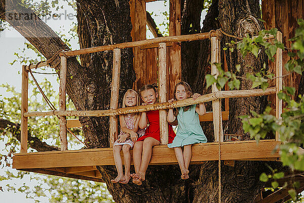 Girls sitting side by side on tree house