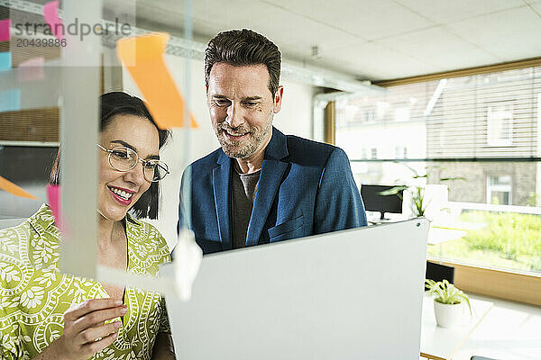 Smiling mature business colleagues discussing over laptop in office