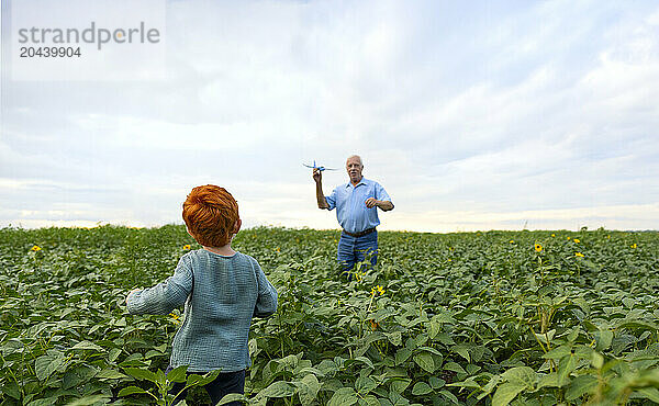 Elderly man playing with grandson in field