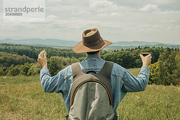 Man with arms outstretched standing at meadow