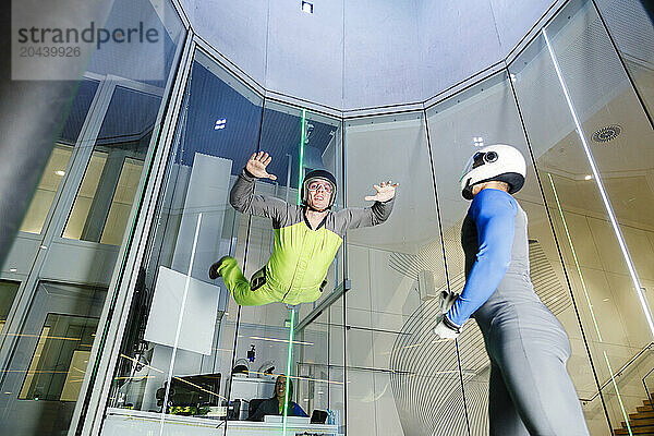 Man enjoying indoor skydiving with instructor at center