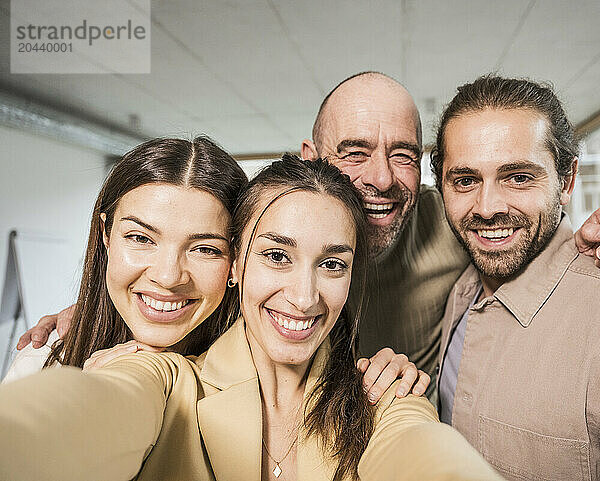 Businesswoman taking selfie with colleagues at office