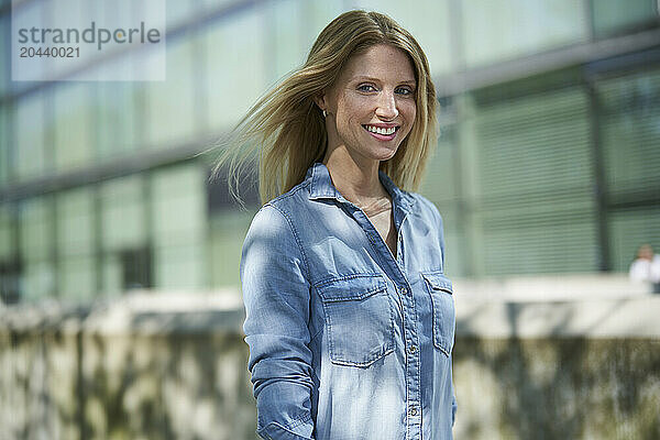 Smiling blond hair woman in front of building