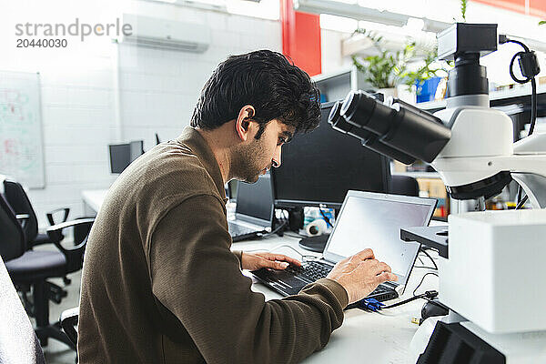 Confident scientist using laptop in lab office