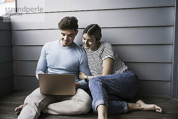 Smiling young couple using laptop together