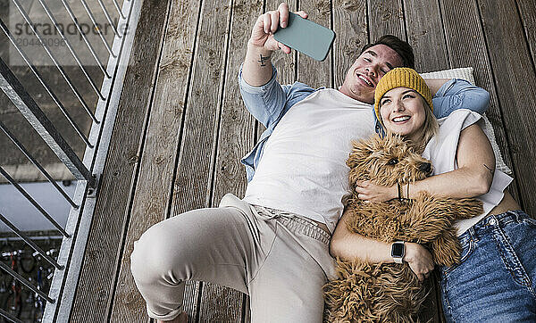 Happy young man taking selfie with woman on balcony