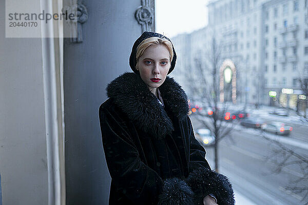 Beautiful woman wearing black winter coat and standing in balcony