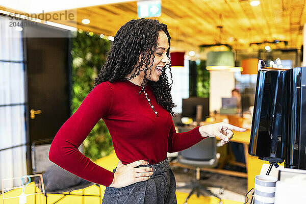 Happy businesswoman operating espresso machine at coworking space