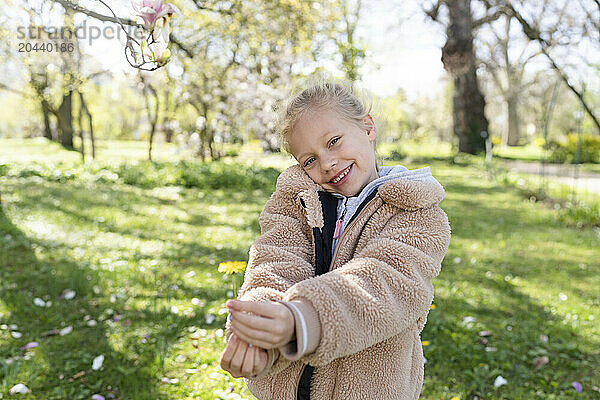 Cheerful girl holding spring flower at park