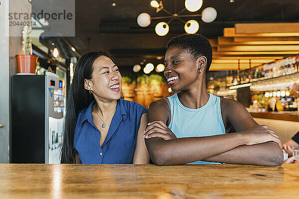 Happy multiracial friends sitting at table in cafe