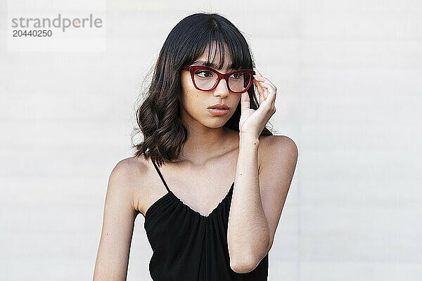 Young woman wearing eyeglasses in front of white wall