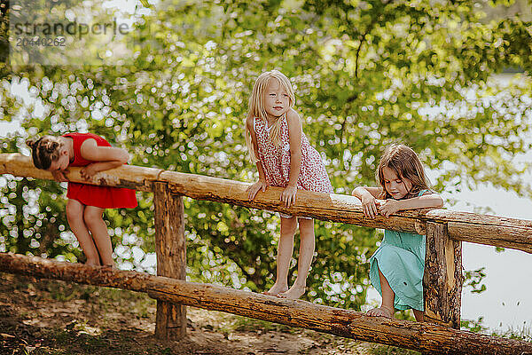 Girls climbing wooden fence at garden