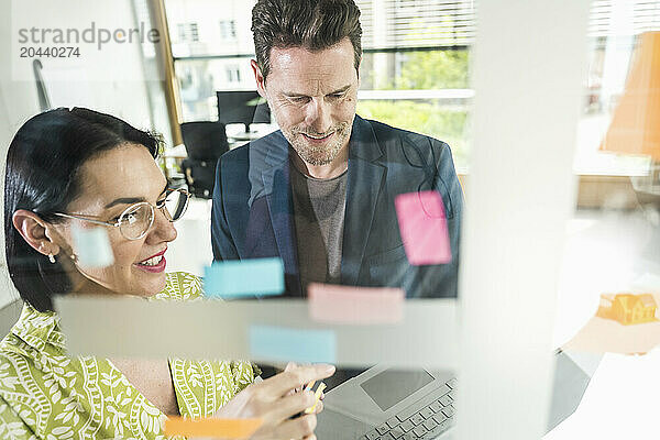 Mature business colleagues discussing over laptop in office