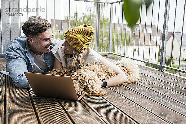 Happy man and woman lying on floor with laptop