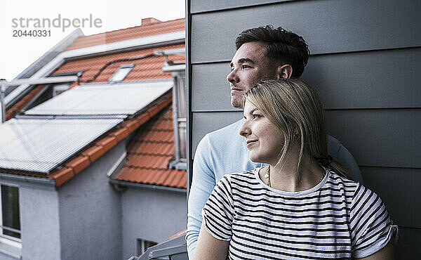 Thoughtful young couple leaning on wall on balcony