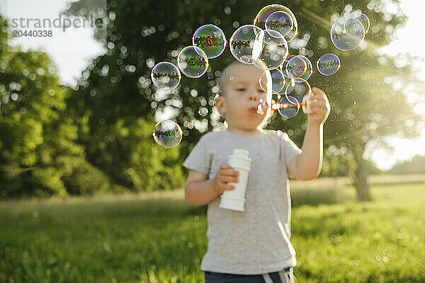 Boy blowing bubbles in garden