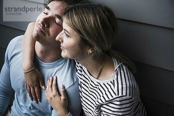 Smiling young woman sitting with man on balcony