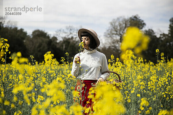 Young woman smelling rape seed flower in field