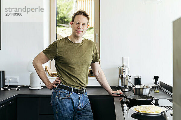 Smiling man cooking pancake in kitchen at home