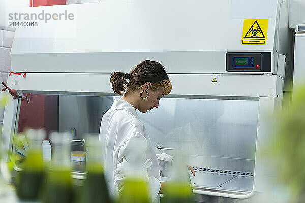 Young scientist in front of fume hood at laboratory