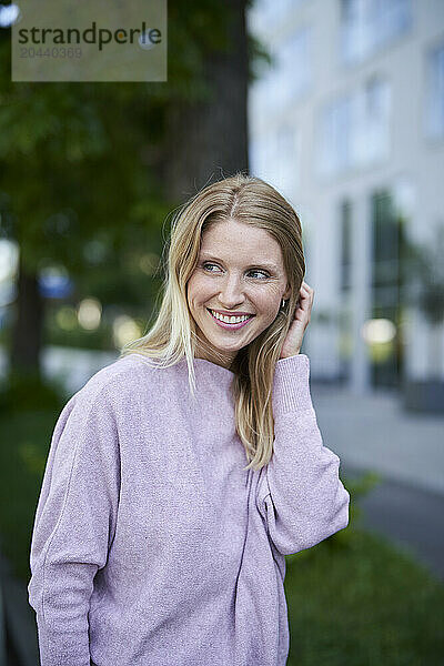 Smiling blond woman with hand in hair