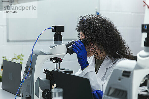 Young scientist using microscope at laboratory