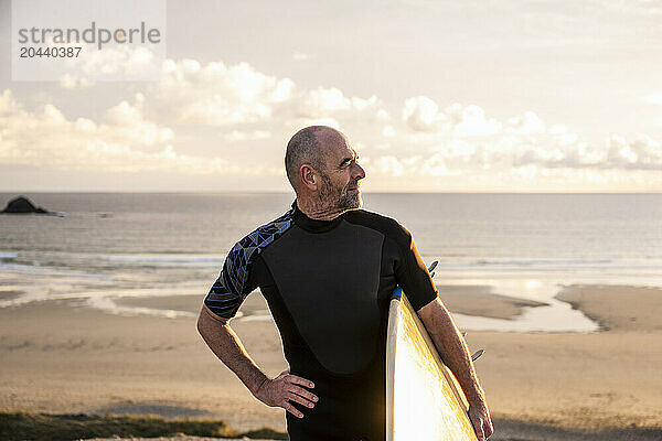 Confident man wearing wetsuit carrying surfboard at beach