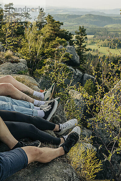 Young friends sitting on rock near trees