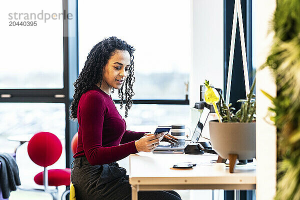 Businesswoman doing online shopping with credit card and laptop at office