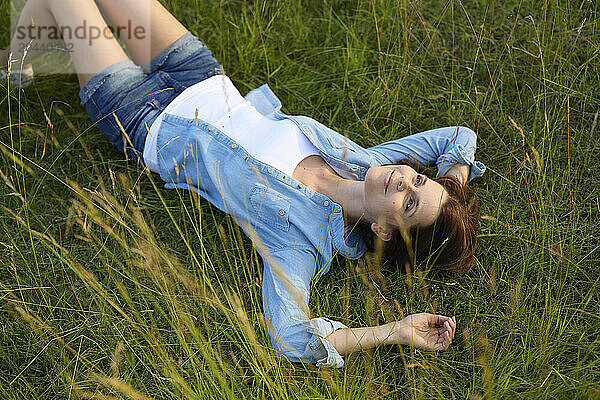 Beautiful woman wearing denim jacket and lying on grass