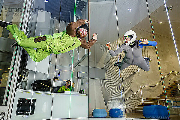 Instructor with man flying at indoor skydiving center