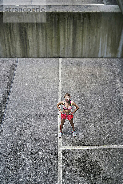 Determined sportswoman standing with arms akimbo