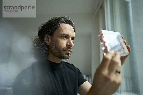 Confident businessman examining glass object in office