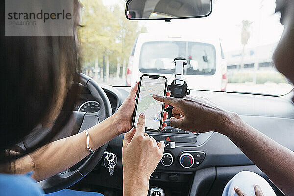 Multiracial female friends using GPS on smart phone in car