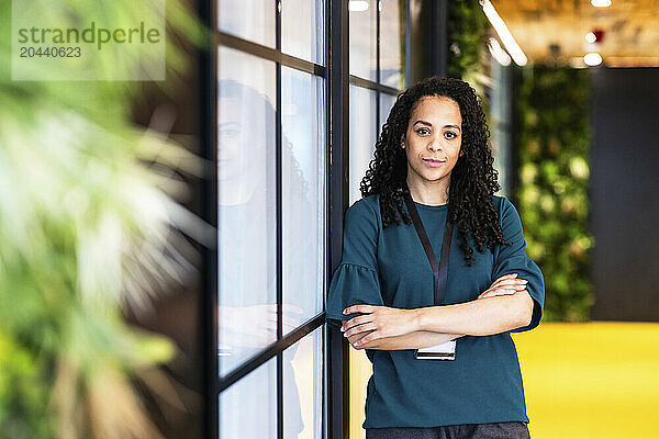 Confident businesswoman standing with arms crossed at coworking space