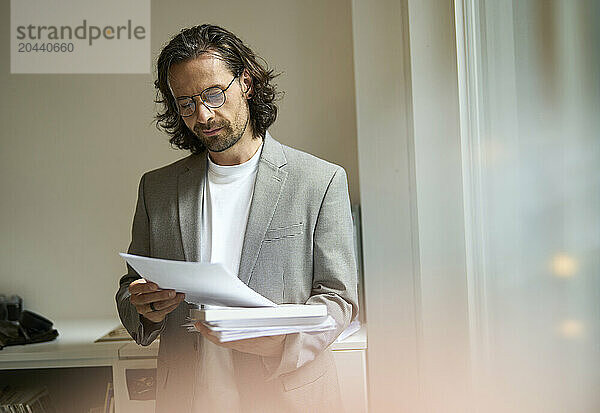 Confident businessman analyzing document at office