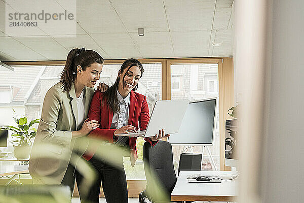 Businesswoman using laptop with coworker at office