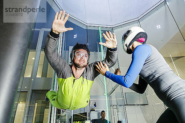 Instructor giving training to man at indoor skydiving center