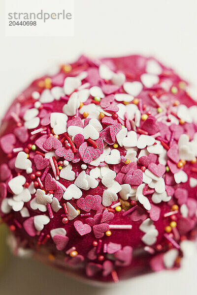 Red color cake with heart shaped sprinkles over white background