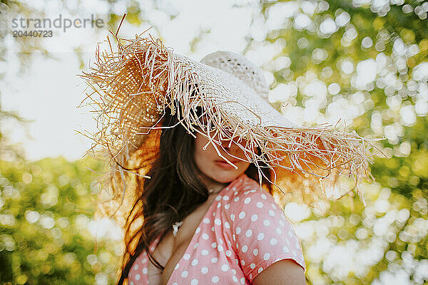 Woman obscuring face with straw hat