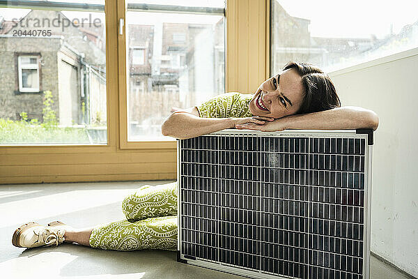 Smiling mature businesswoman leaning on solar panel at office