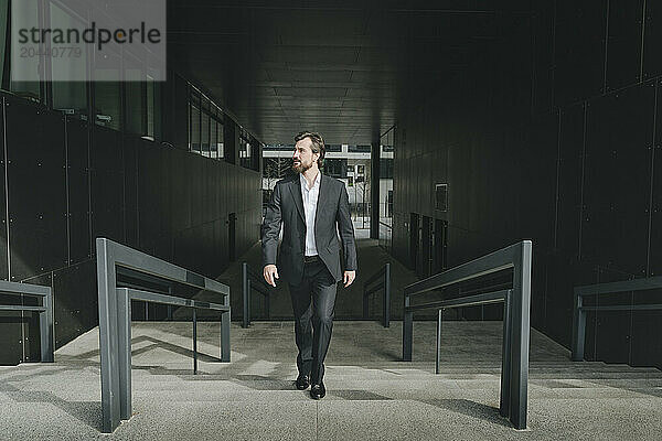 Confident businessman moving up stairs in office building