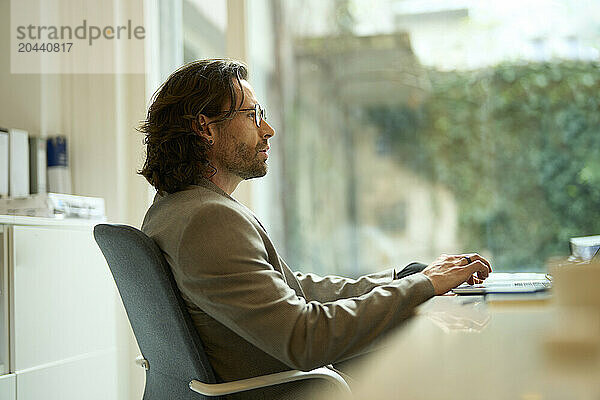 Confident mature businessman working at desk in office