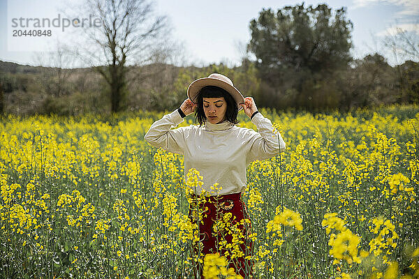 Young woman wearing hat standing in rape field