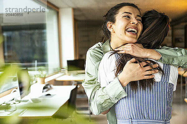 Happy young businesswoman embracing colleague in office