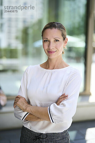 Confident businesswoman with arms crossed in front of building