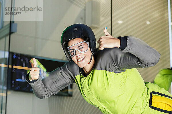 Happy woman gesturing thumbs up at skydiving center